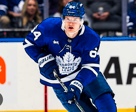 A hockey player wearing a blue Toronto Maple Leafs jersey, number 84, skates with the puck during a game.