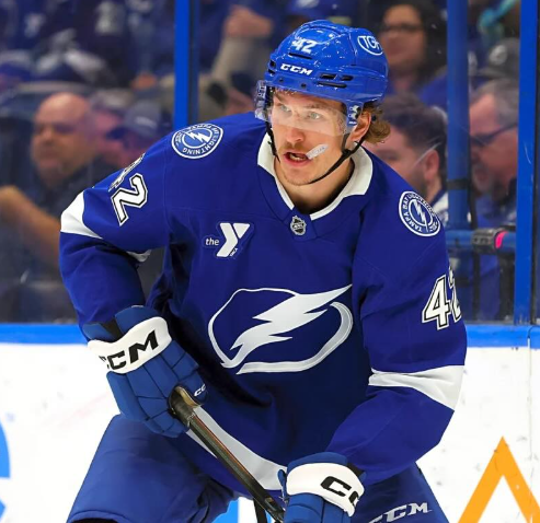 A hockey player wearing a blue jersey with the number 42, preparing to play on the ice rink.