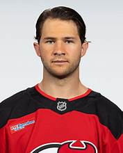 Headshot of a male hockey player wearing a red team jersey with the logo of a professional hockey team.