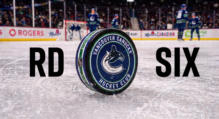 A Vancouver Canucks hockey puck on the ice with the words 'RD' and 'SIX' displayed beside it.